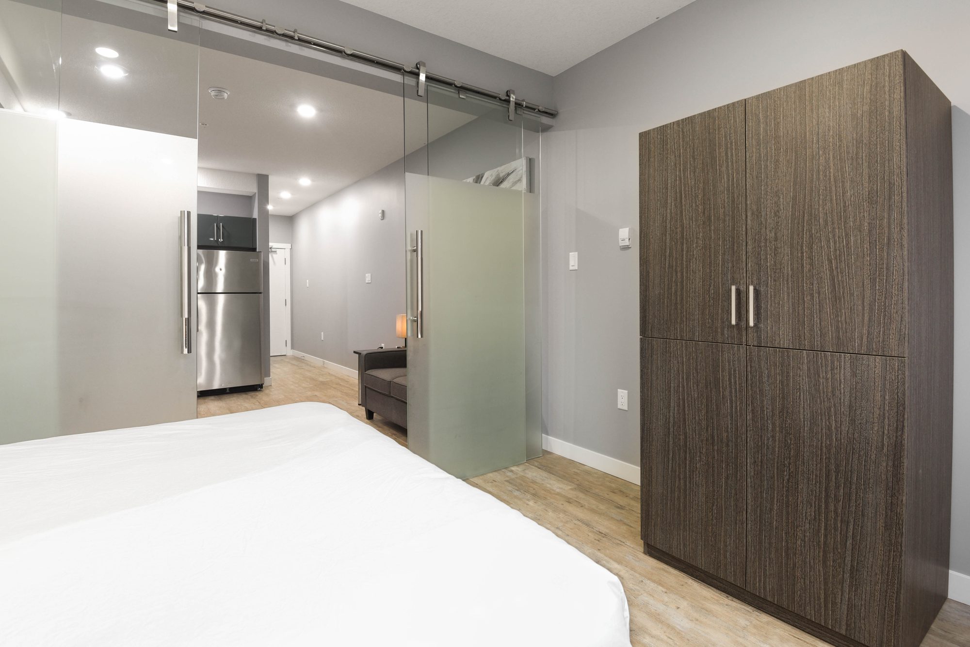 Bedroom with wardrobe cabinet, refrigerator visible in the open-plan suite