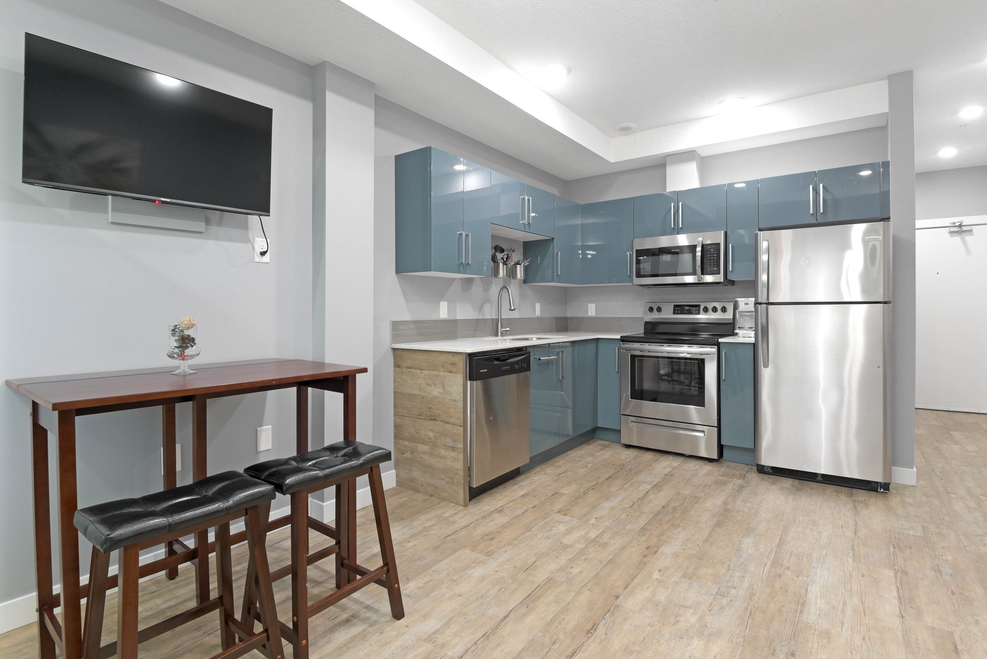 Kitchen with dining table, stainless steel appliances, and wall-mounted TV