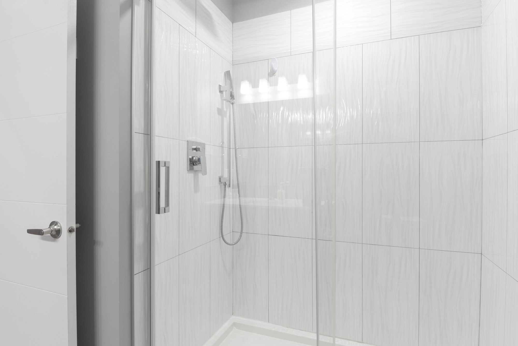 Bright tiled walk-in shower with glass door in a one bedroom suite
