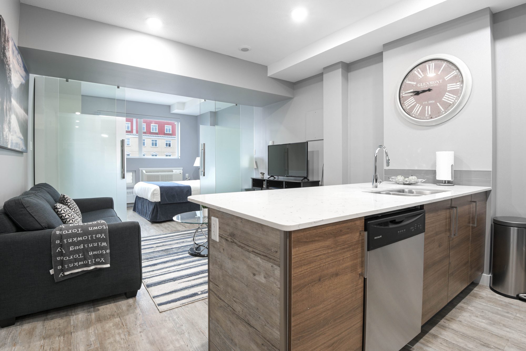 One bedroom living area with sofa, kitchen island, and stainless steel dishwasher