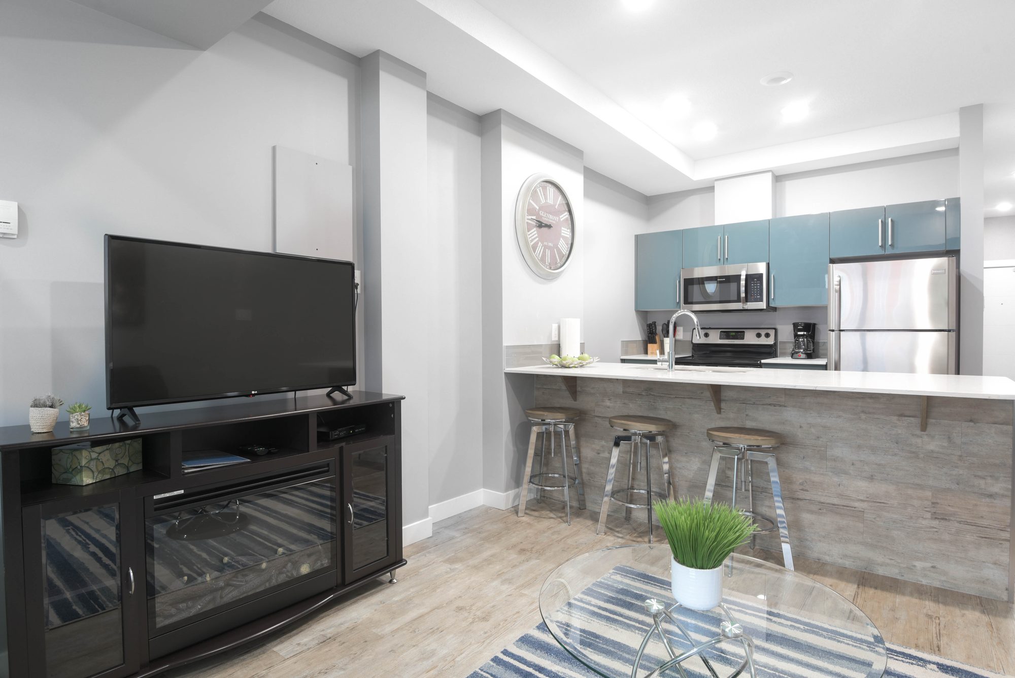 Living area with TV console and open kitchen with breakfast bar seating