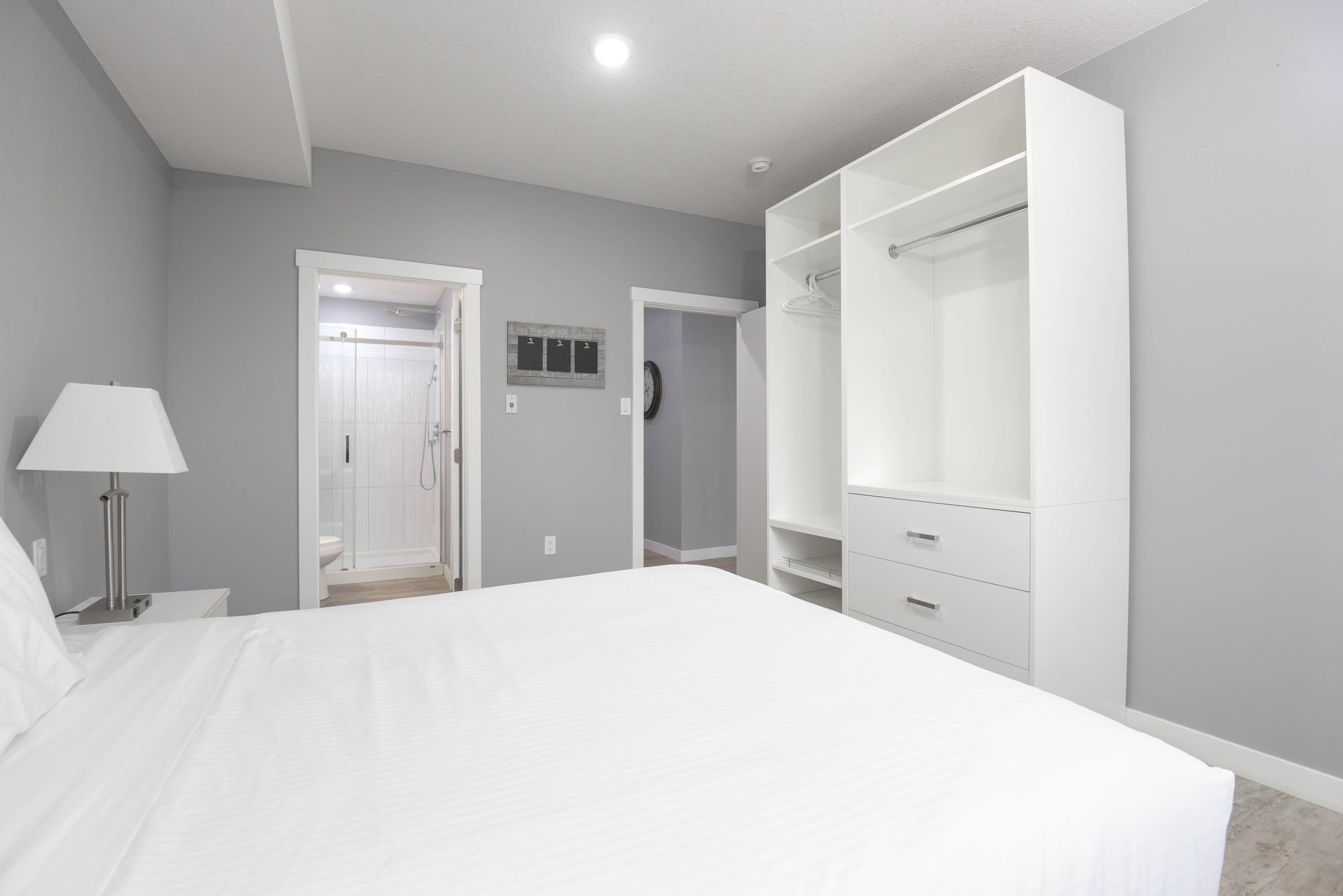 Bedroom with open white wardrobe and view toward the suite entry
