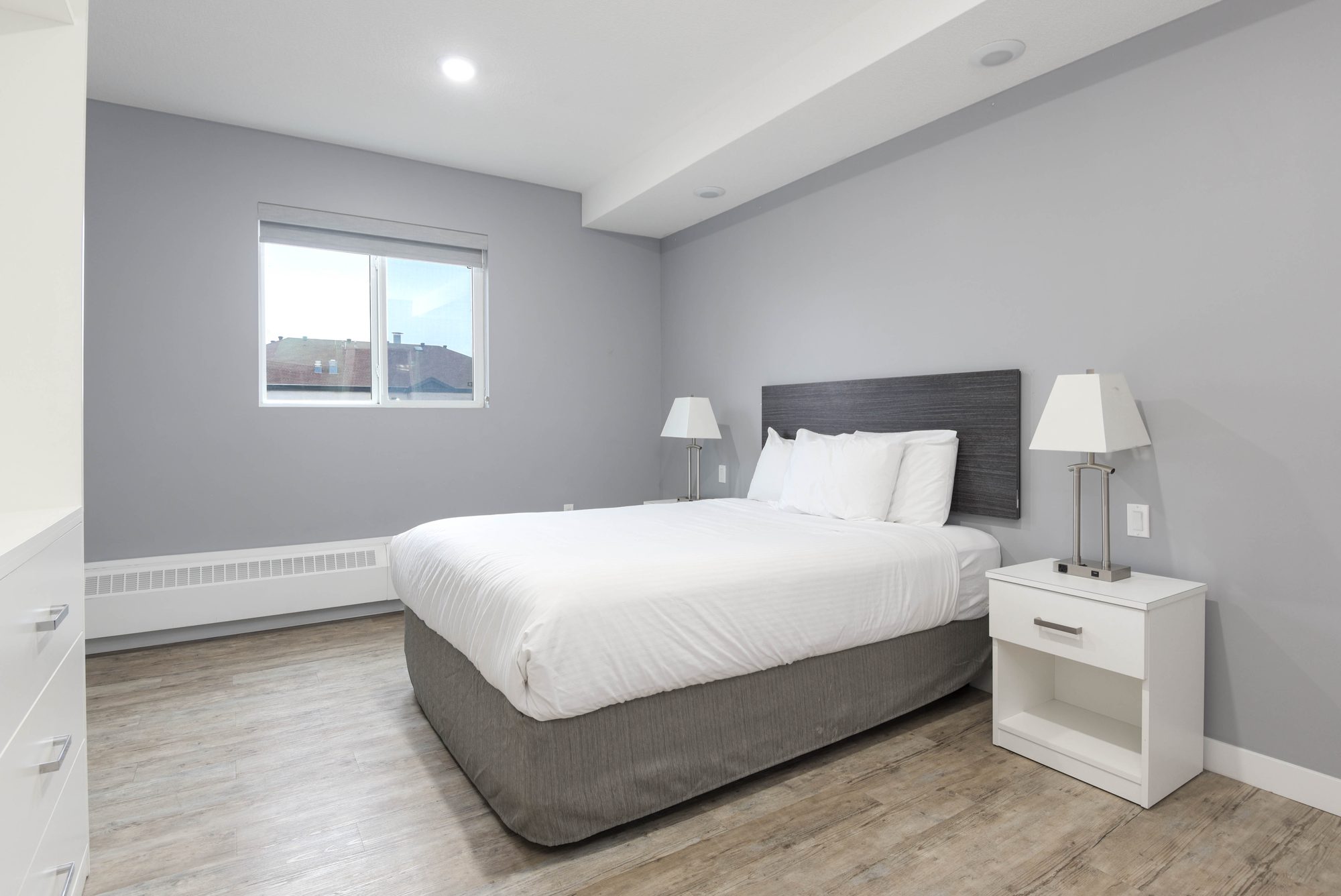 Bedroom with dark upholstered headboard, white bedding, and bright window