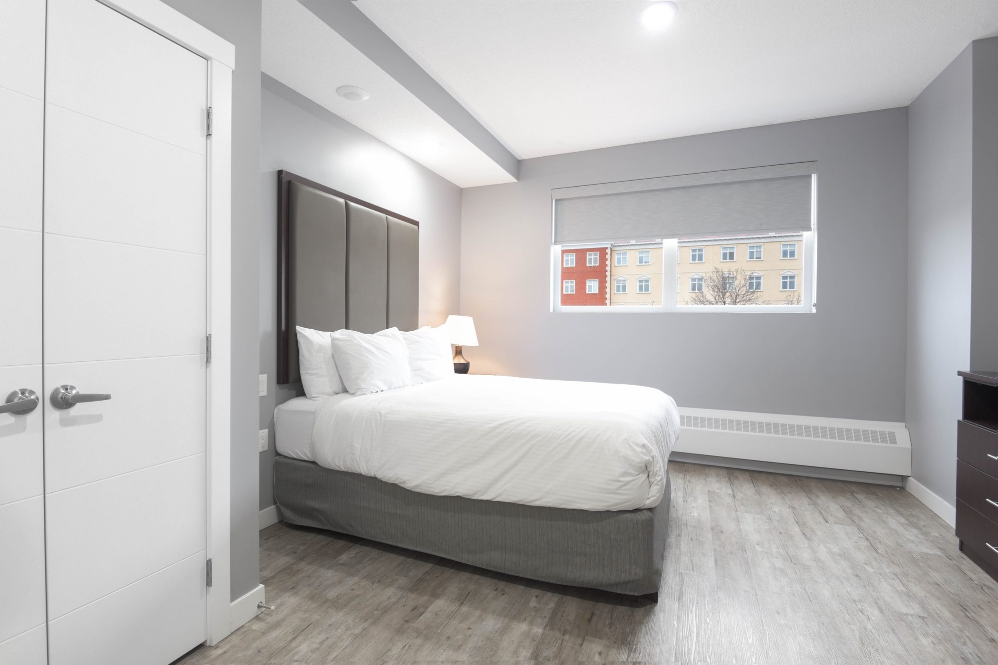Second bedroom with padded headboard and baseboard heater below the window